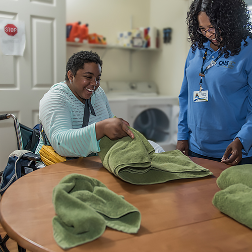 Patient working with NRS staff to learn to fold laundry.