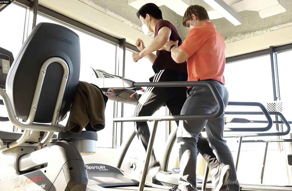 Image of CNS patient on treadmill with physical therapist.